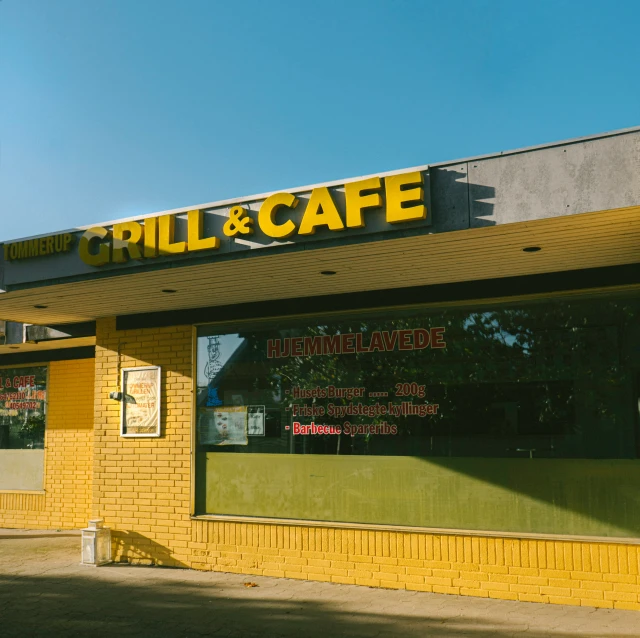 a yellow restaurant with large window next to a small parking meter