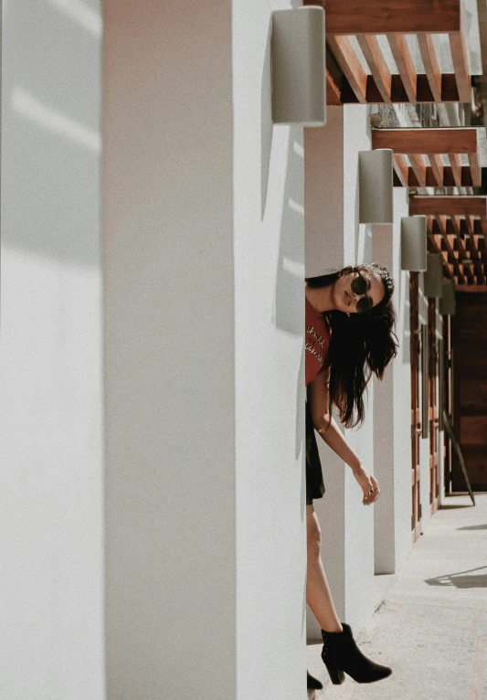 a woman standing on the side of a building next to columns