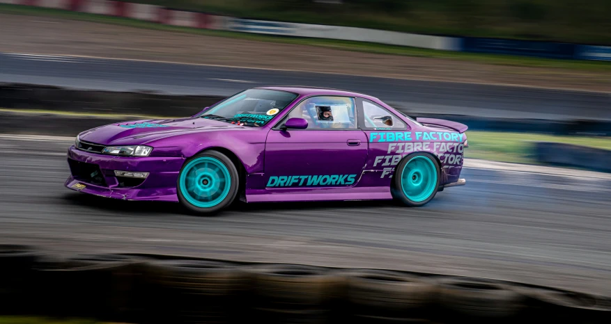 a drag car with green rims driving on a track