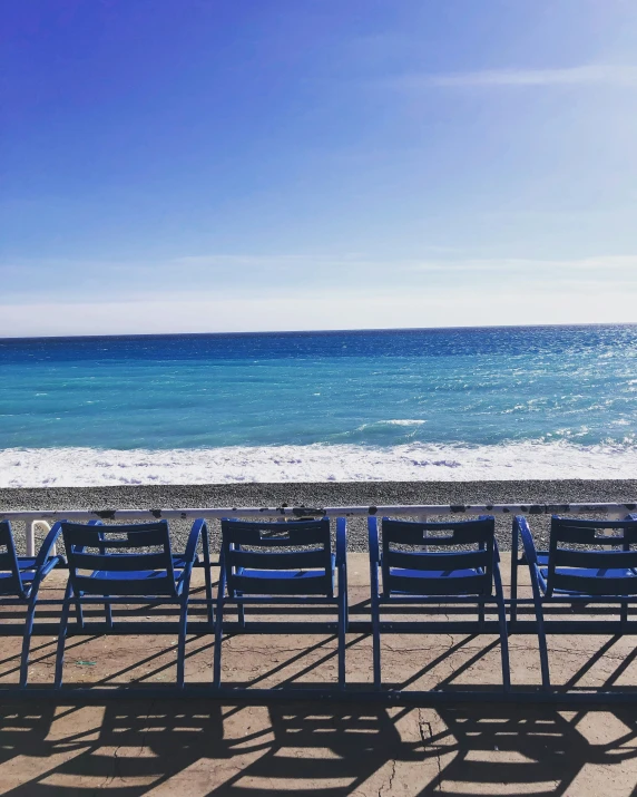 rows of empty chairs sitting on a beach near the water