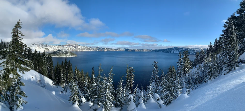 a blue sky over a deep blue lake surrounded by trees