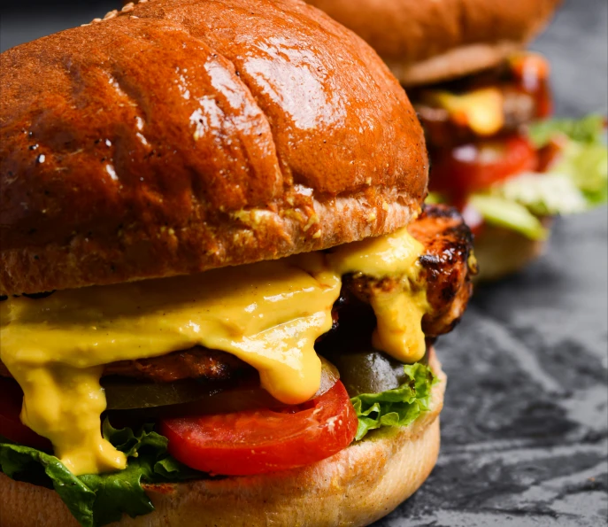 two sandwiches covered with cheese and vegetables on a table