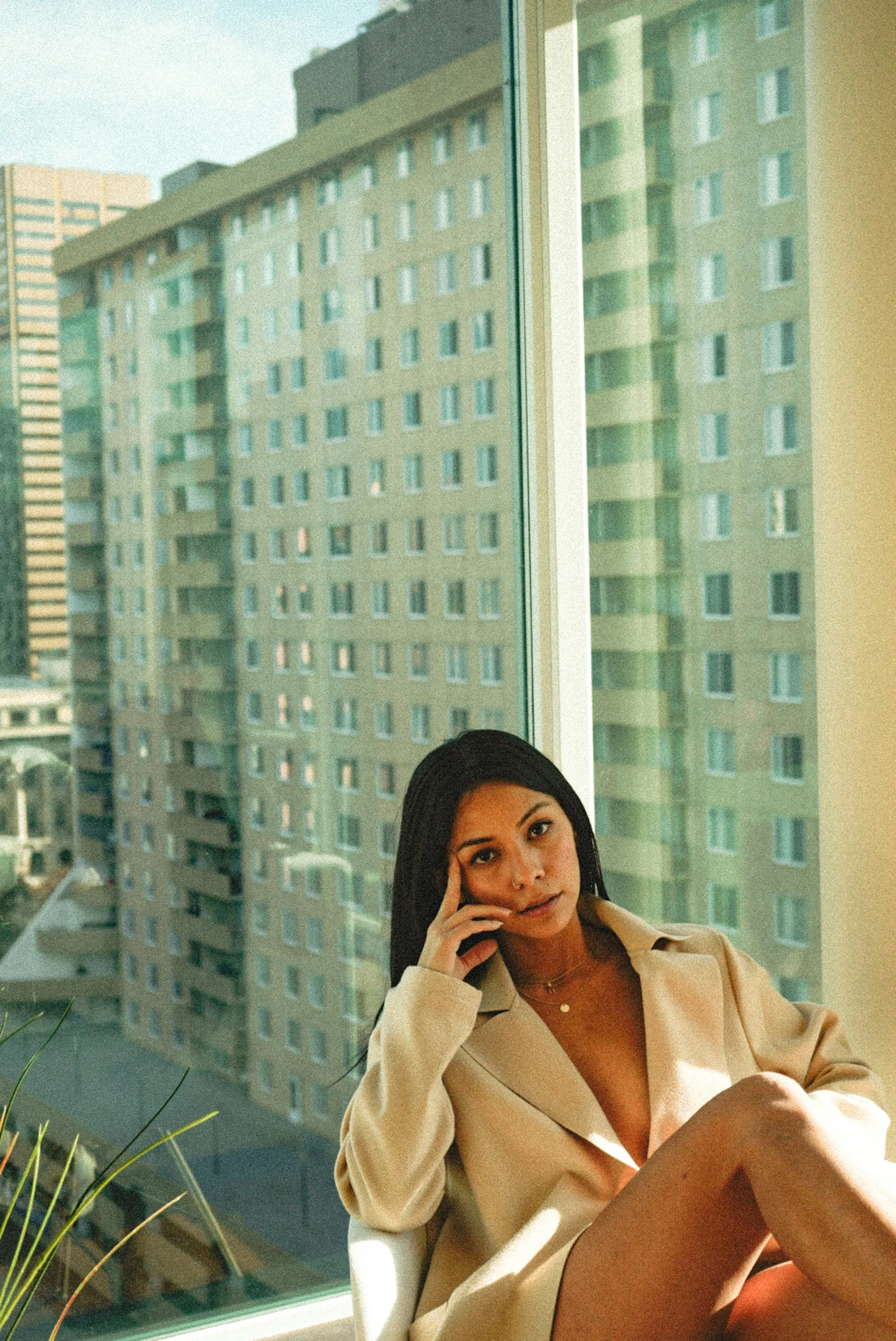 a beautiful young lady sitting down in front of a window