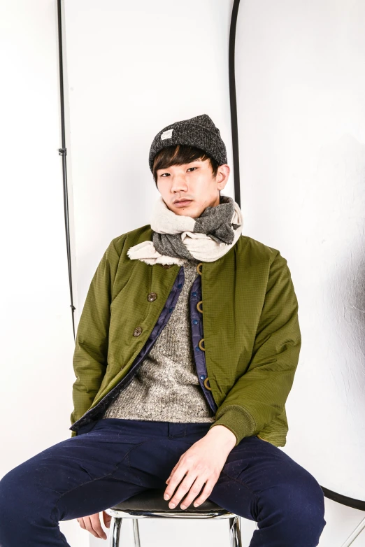 a man is wearing a hat and sweater while sitting on a chair