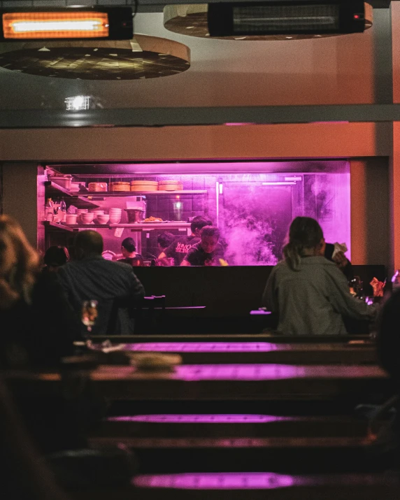 a group of people sitting at a restaurant table in front of a big window