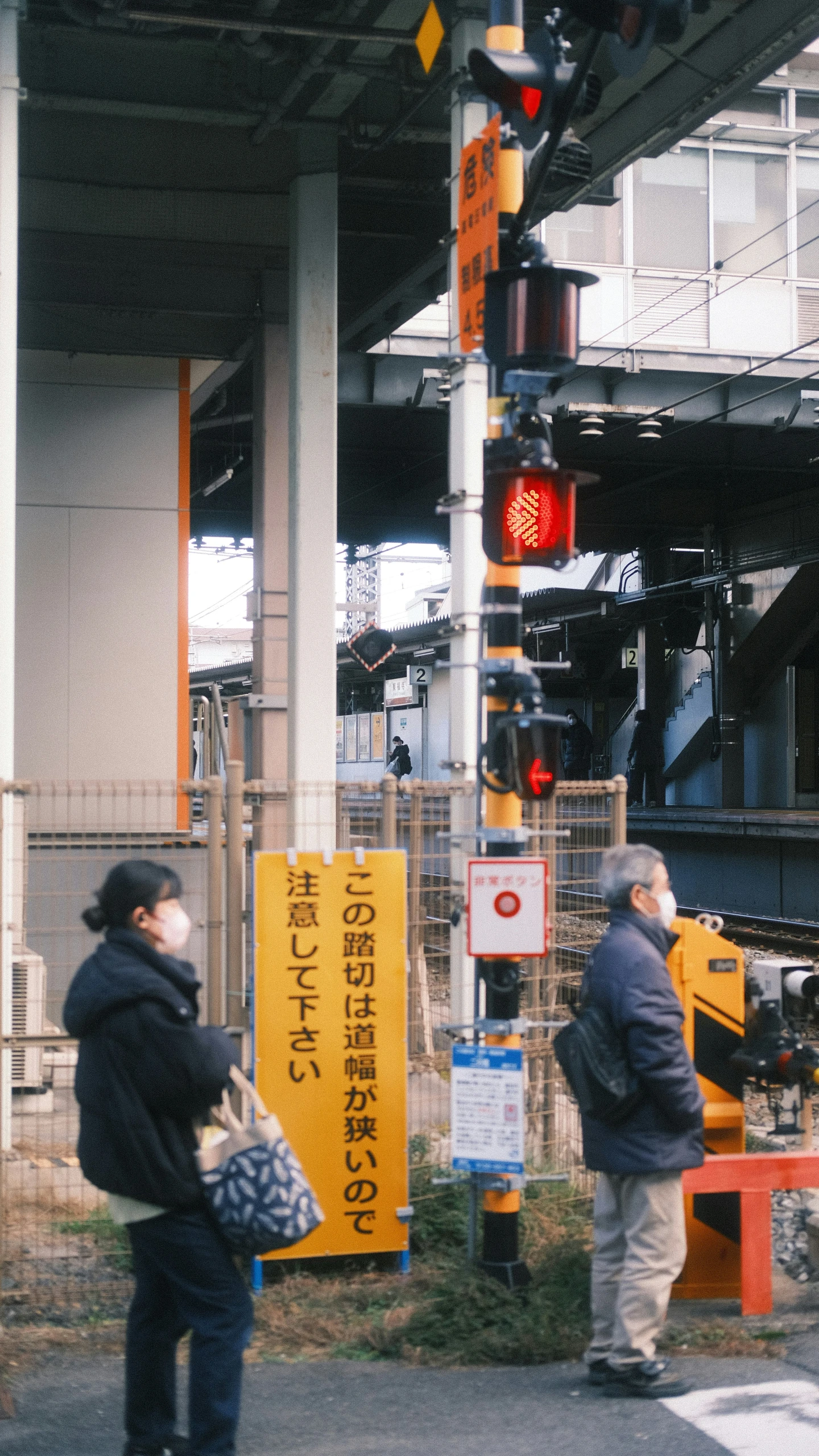 people in an area under a train station waiting to cross