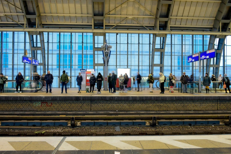 a group of people stand at the train station waiting for their luggage