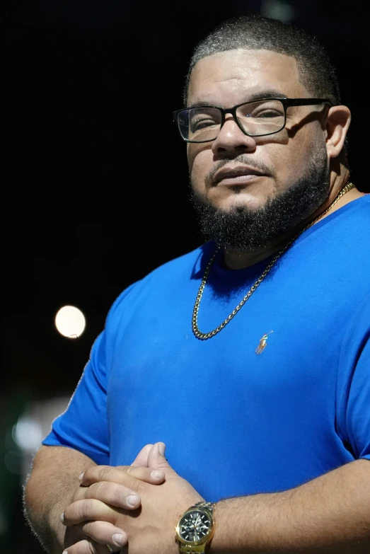 a man in blue is wearing glasses with a watch on his wrist