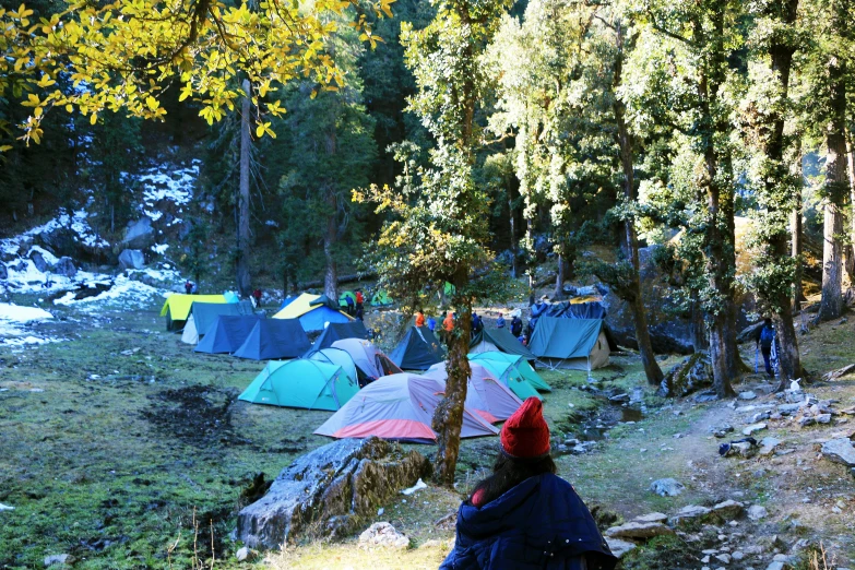 a person with a red hat sits in front of some tents