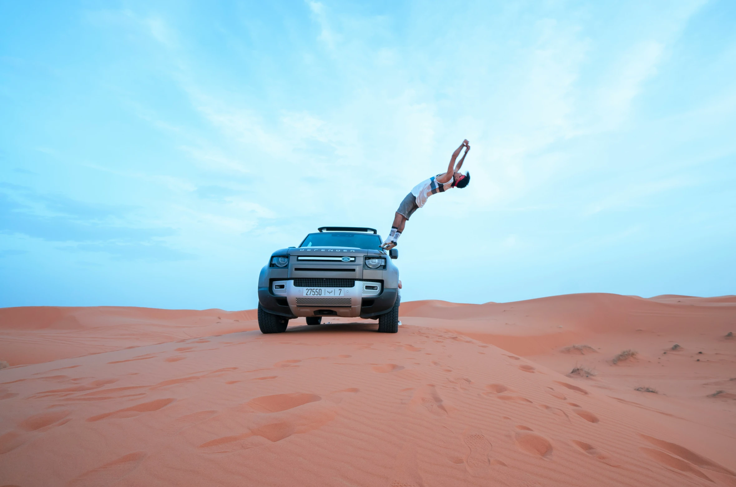 a woman jumps off a truck in the sand