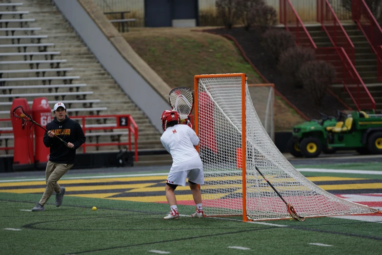 two people playing lacrosse in front of some bleachers