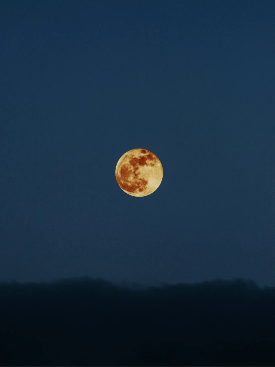 a blue sky with a large yellow full moon in the middle