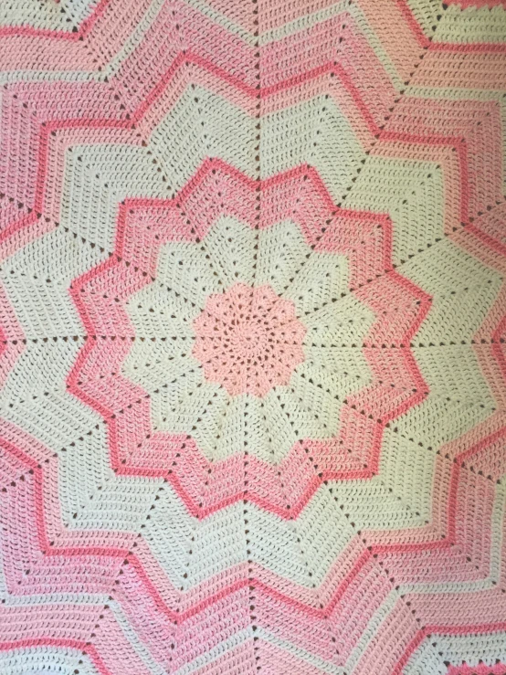 a large pink and white crocheted blanket