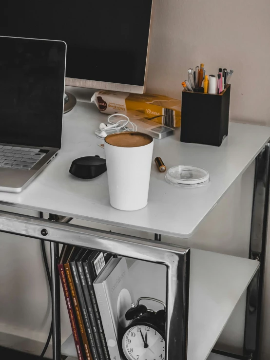 a desk with a monitor, clock and other items