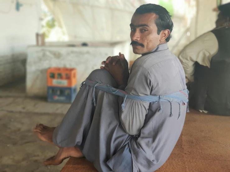 a man sits in a room holding a rope