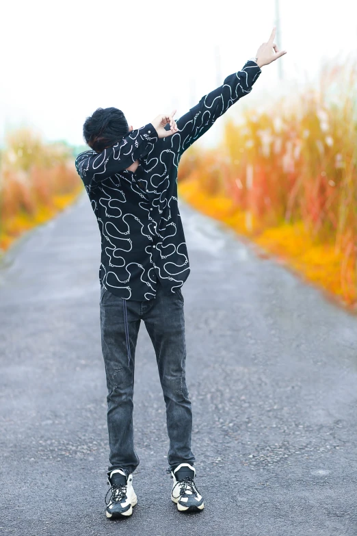 a young man stands on a path pointing to the sky