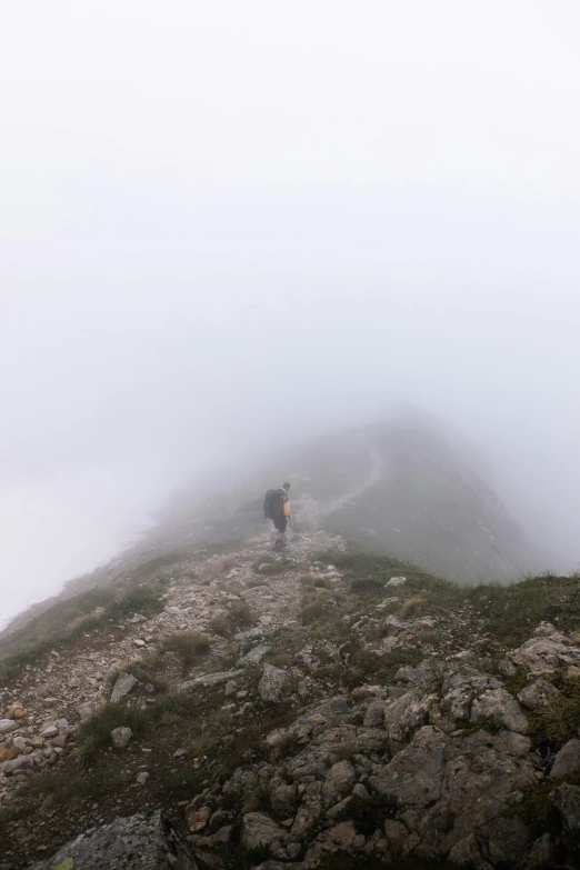 two people stand on a rocky path in the fog