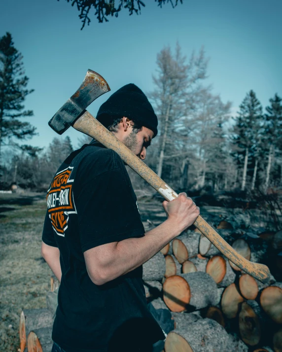 a man with an old style axe standing in front of logs