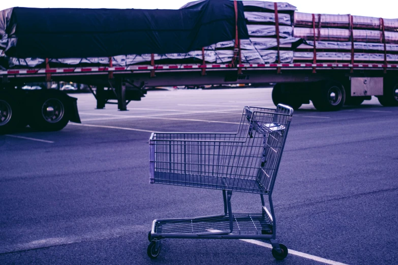 a shopping cart sitting on the side of a road next to a truck