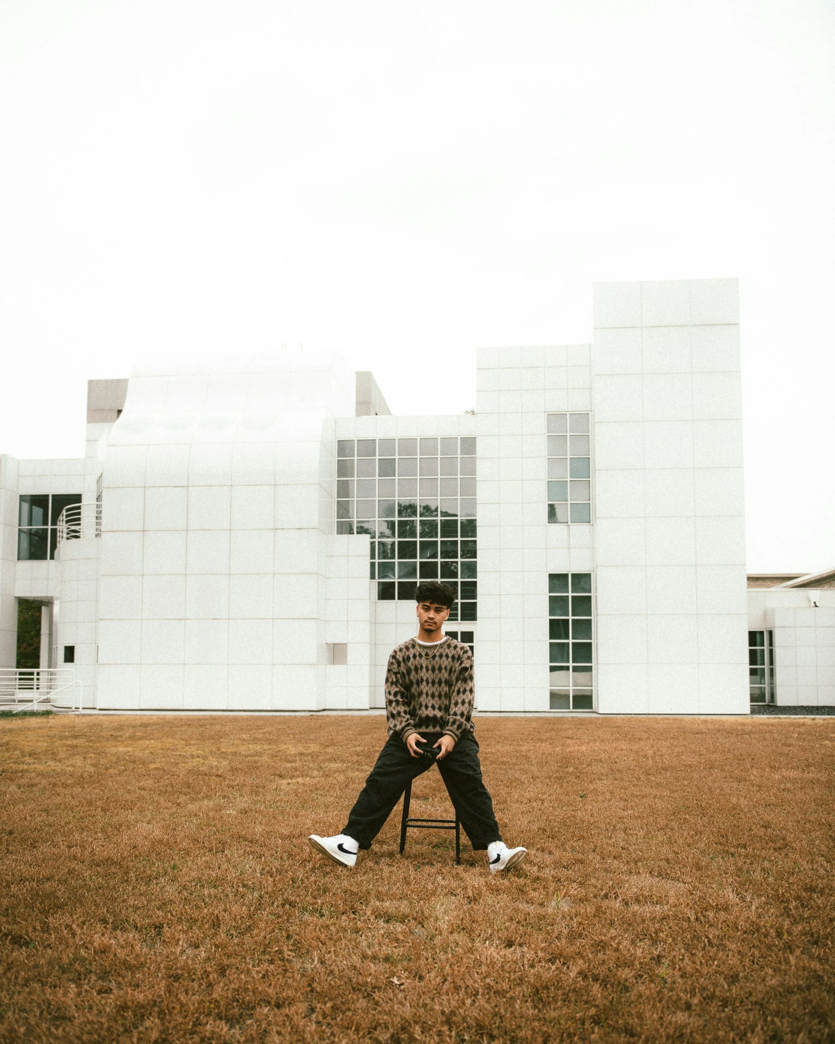 a man poses in front of a white building