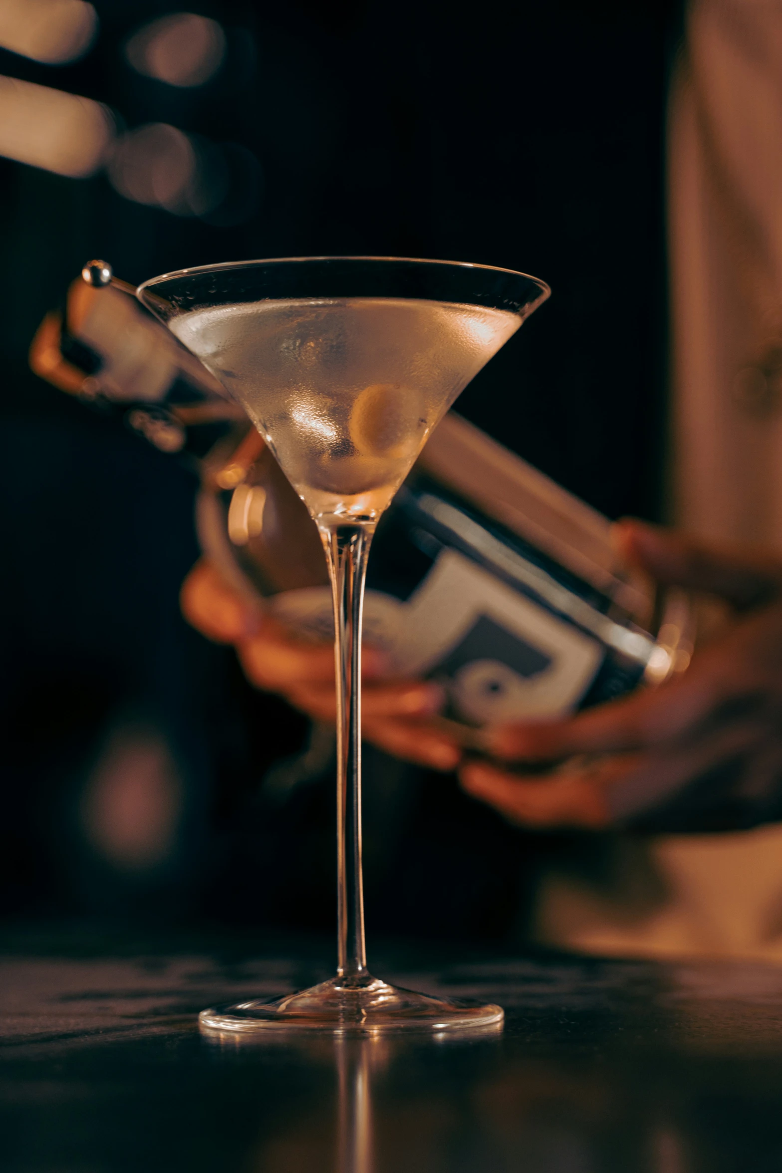 an empty martini glass with two bottles in the background