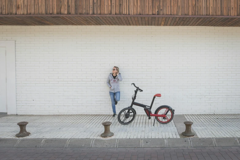 man standing beside two bikes leaning against a brick wall