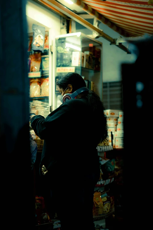 a man stands at a market while looking at his cell phone