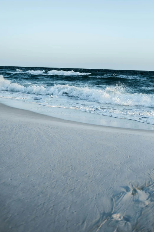 there is a sandy beach with waves in the ocean