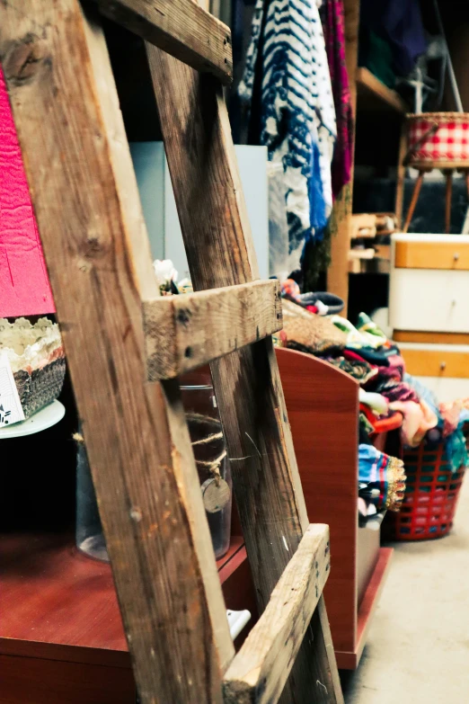 clothes hang on racks next to a wooden ladder