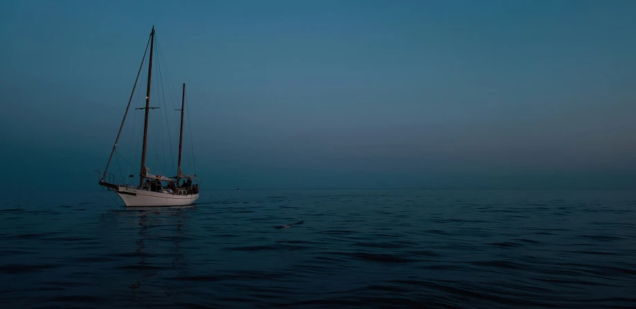 a sailboat floats through a very calm ocean