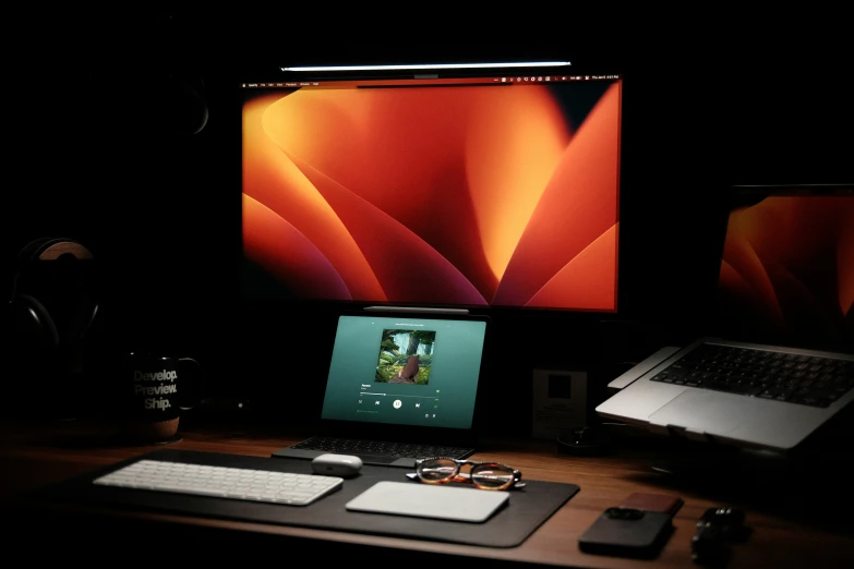 an image of a desktop and laptop set up in the dark