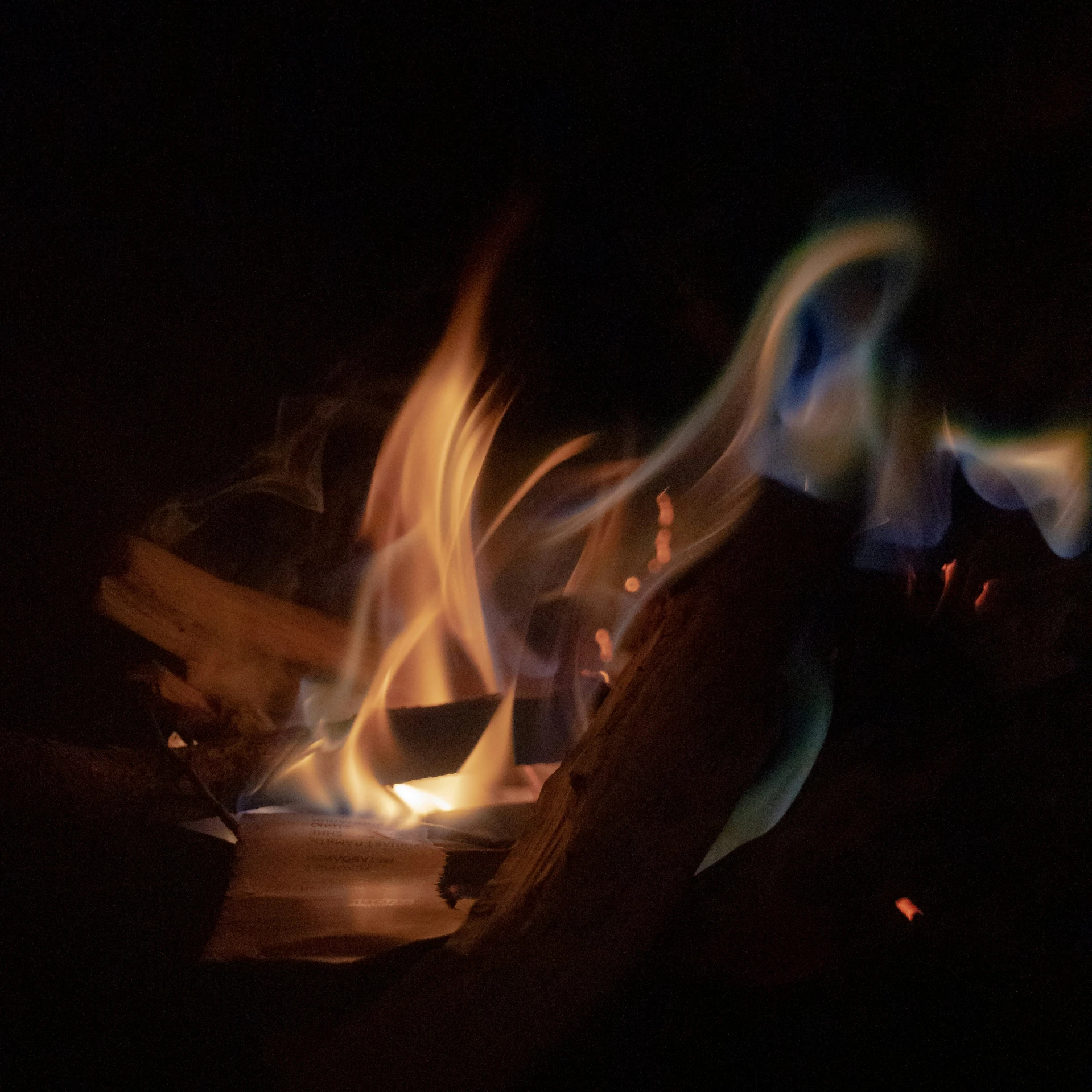 flames rising over a campfire and some people standing around