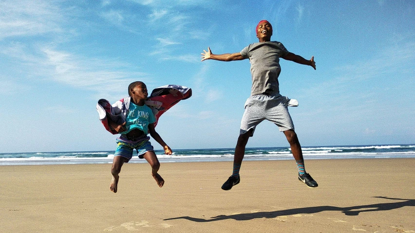 two men jumping in the air on a beach