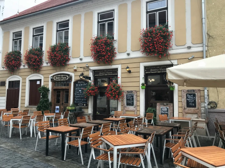 the outdoor restaurant is near the building with lots of seating and flowers