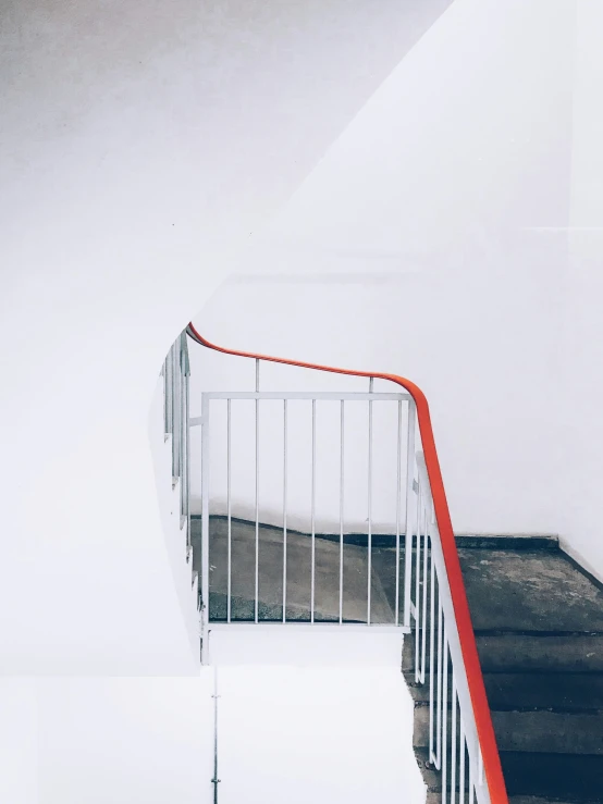 a red railing next to a white stairwell