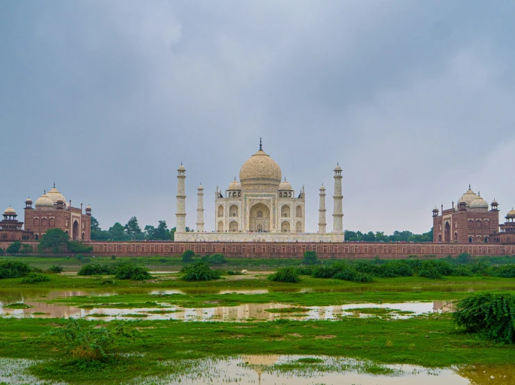 a long building surrounded by green vegetation under a cloudy sky