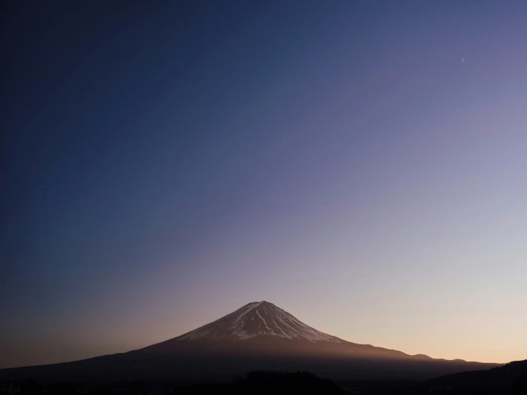 a mountain with a snow capped peak at dusk