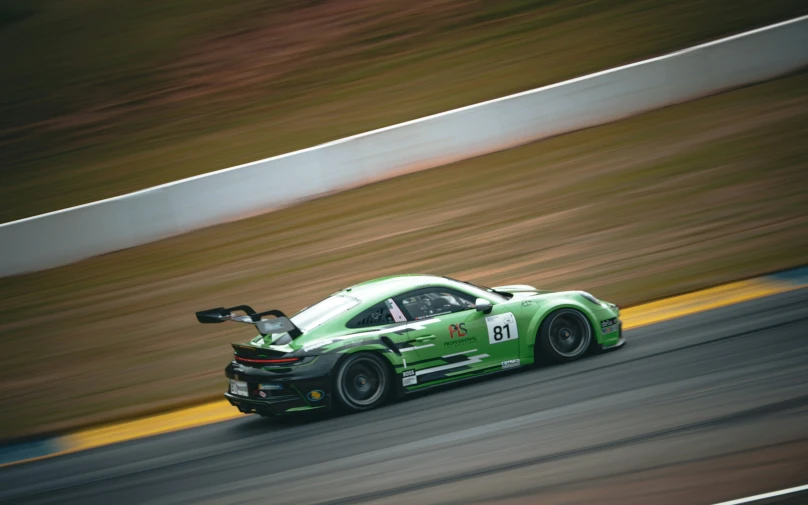 a green sports car speeds around the track