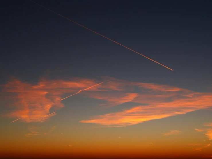 an airplane flying in the sky at sunset