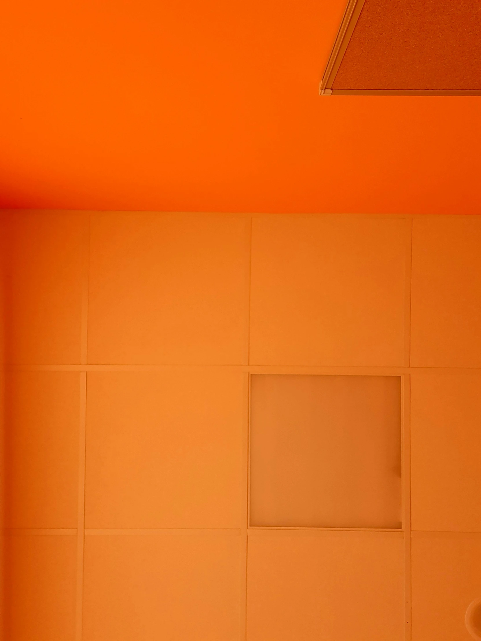 a large orange bath tub in a bathroom with a square mirror above it