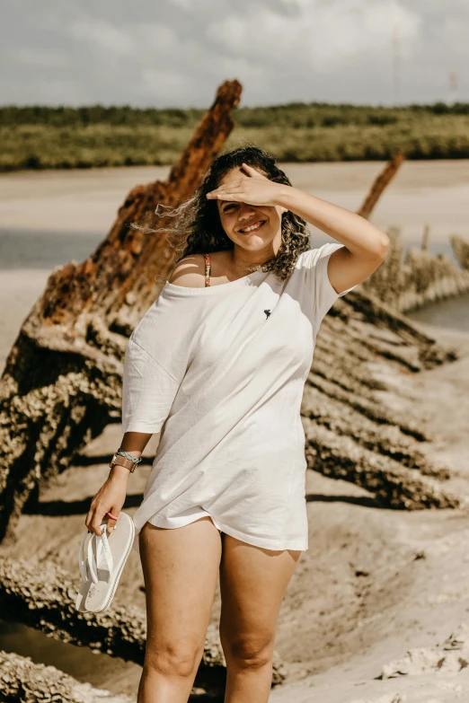 a woman standing next to a fallen tree on a beach