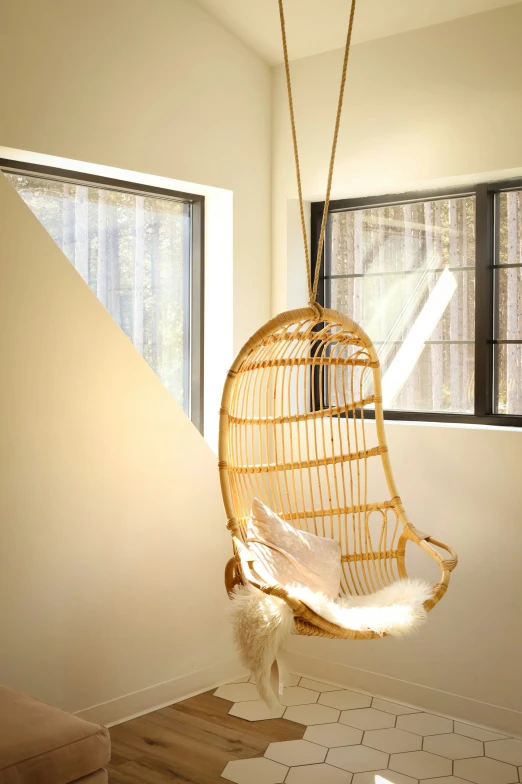 a wicker hanging chair next to an open window