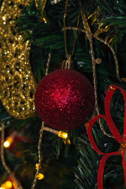 an ornament and bow sitting on a christmas tree