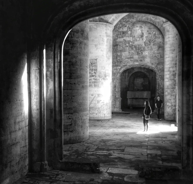 two people walking in an archway between a building