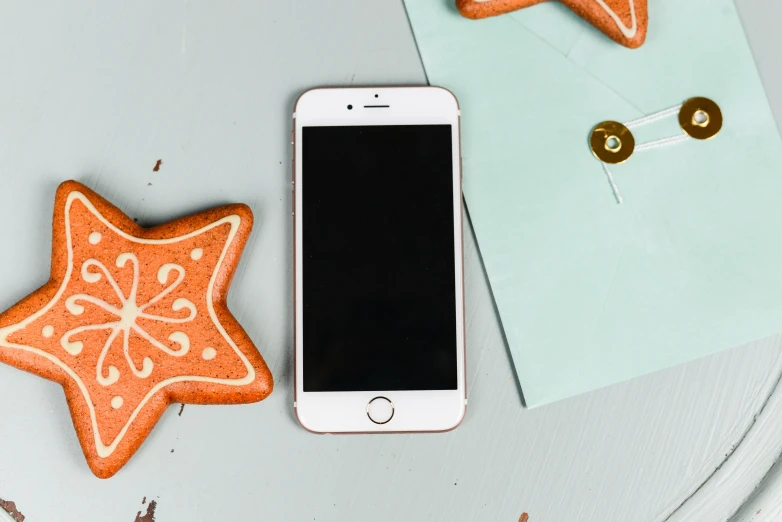 an iphone on a desk next to decorated cookies