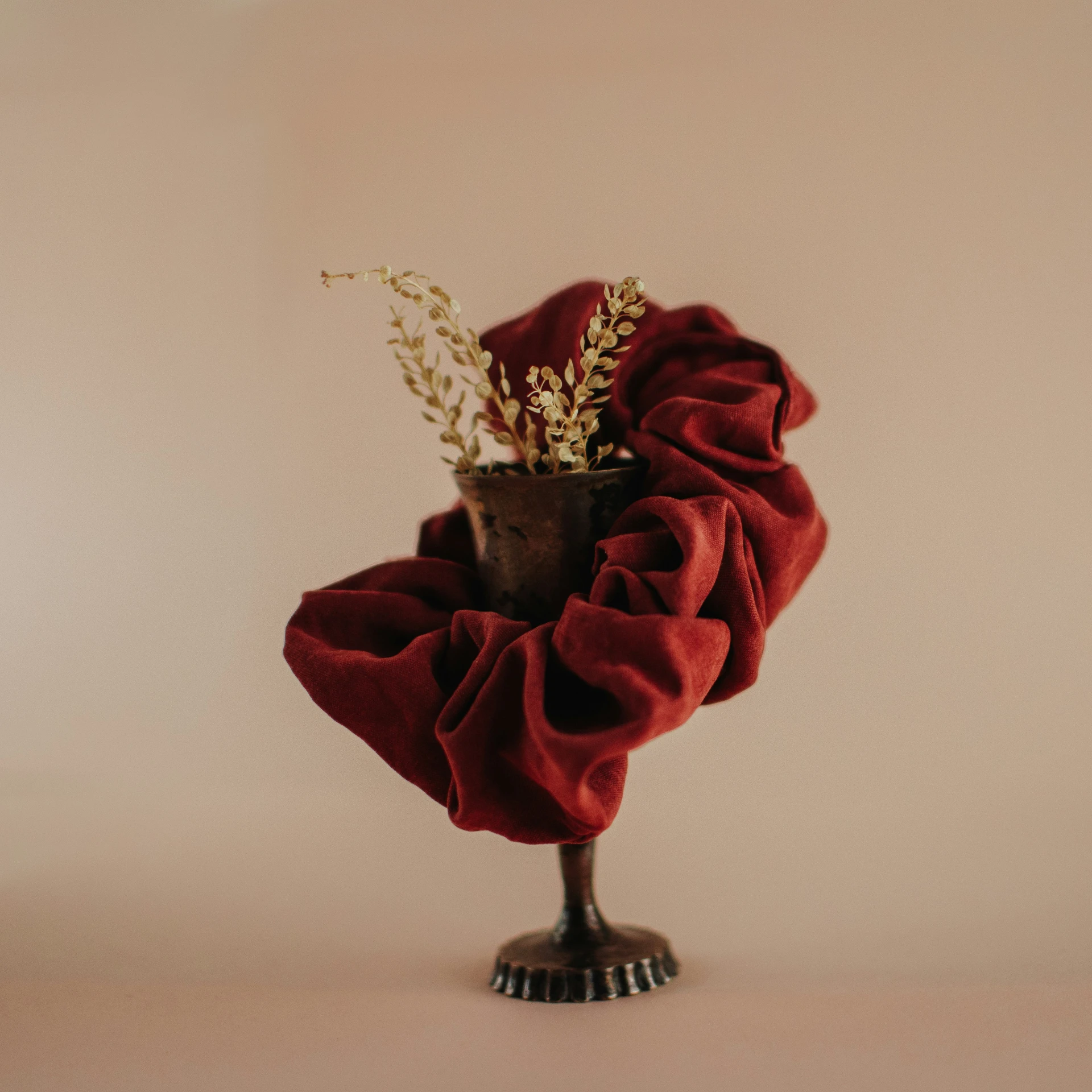 a red fabric wrapped around a vase with plants in it