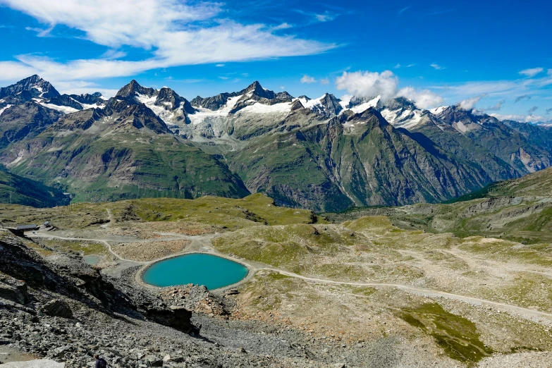 a view of a mountain range with a small lake and snowy mountains