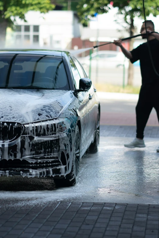 a man washing his car in a driveway