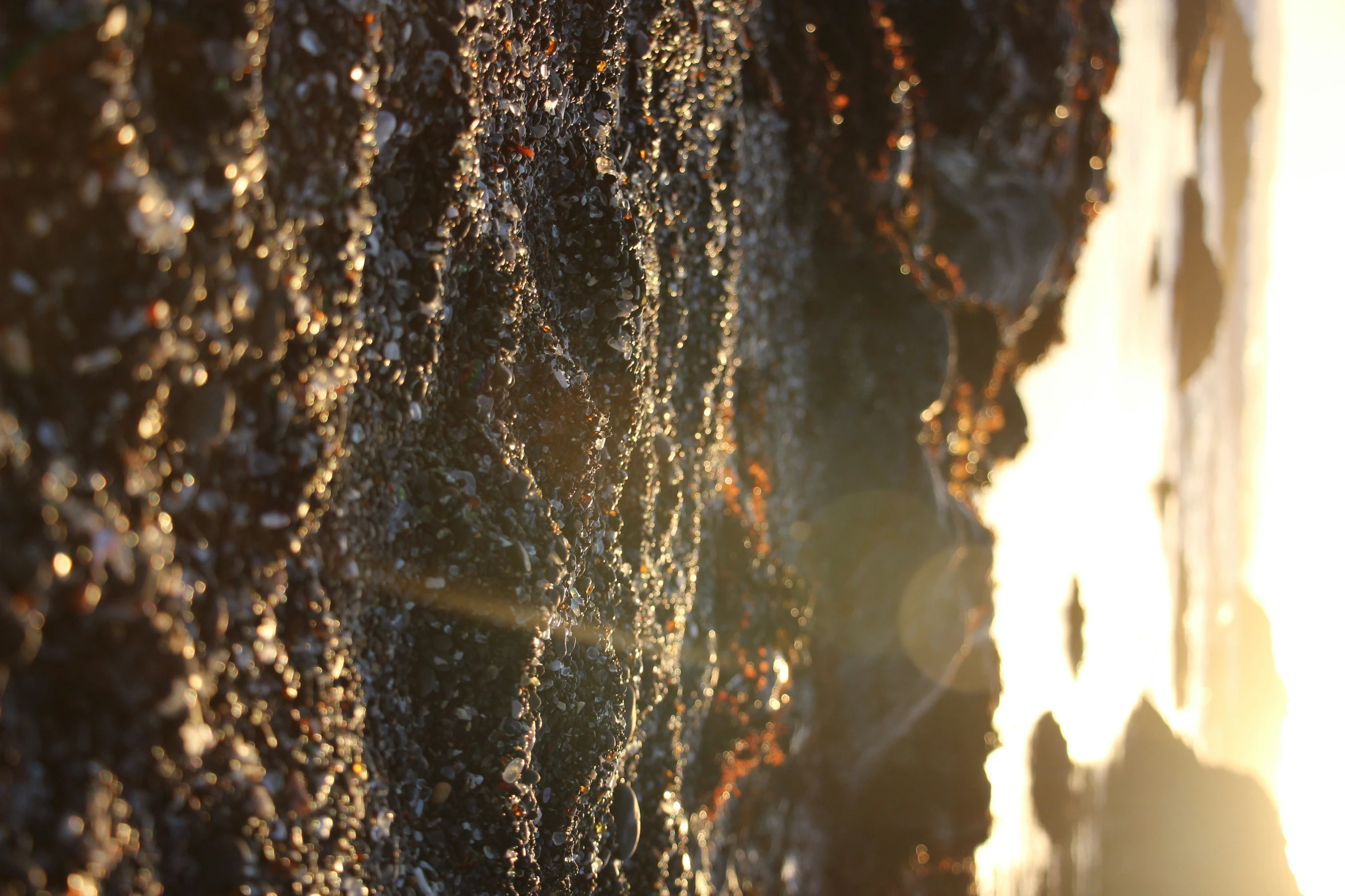 sun shining through a layer of dark rock wall