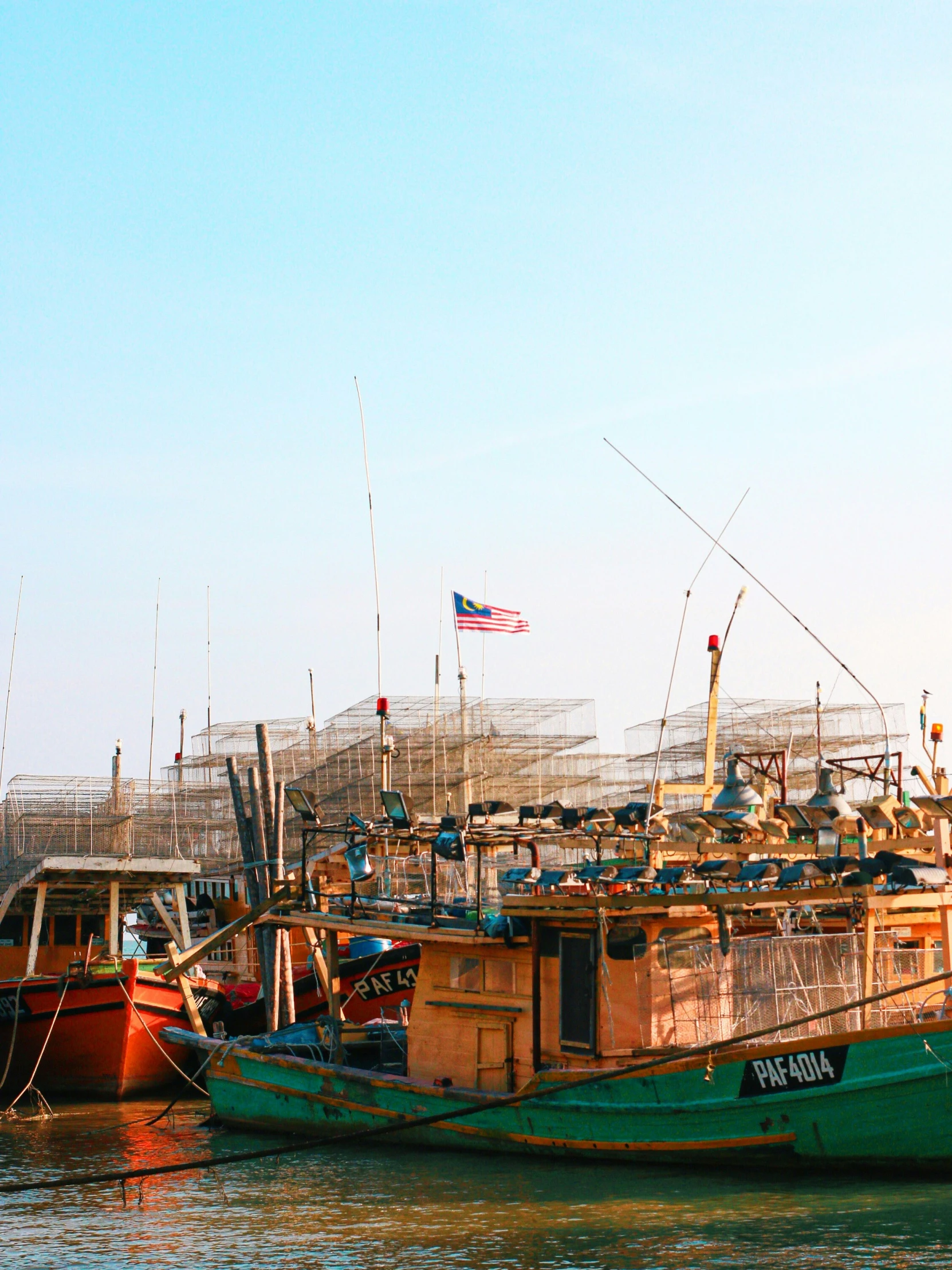 several fishing boats on the water, with a flag in the background